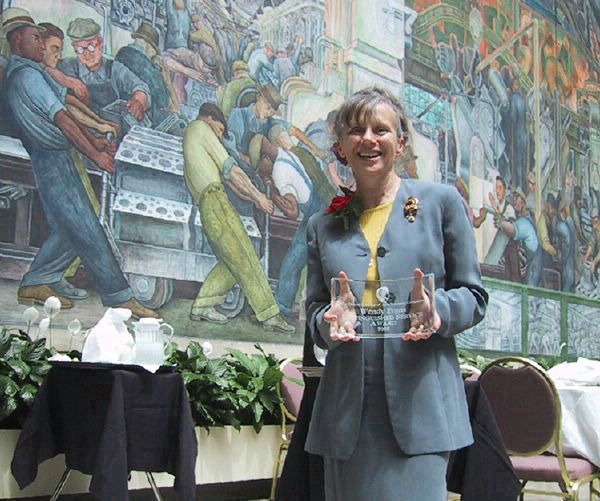 Wendy holding her award in Rivera Court after Volunteer Committee luncheon 